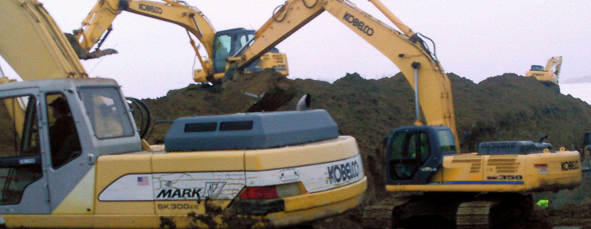 A number of Dahle Enterprises' large excavators digging on a hillside